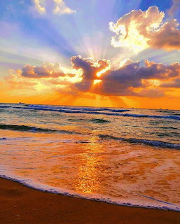 Golden sunset over ocean with waves on beach and dramatic clouds