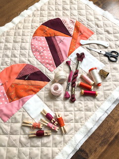 Handmade quilt blocks with sewing supplies on white quilted fabric