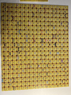 Large yellow patchwork-style patterned textile or artwork hanging on a wall