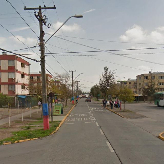 Urban street with apartment buildings, power lines, and pedestrians under a cloudy sky