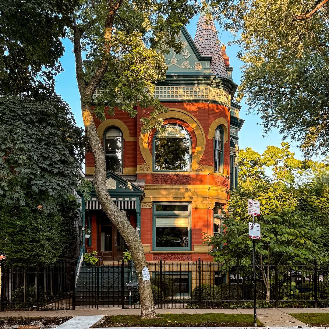 Victorian brick house with turret and ornate architectural details surrounded by trees