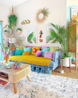 Colorful bohemian living room with yellow couch, rainbow pillows, plants, and wall decor