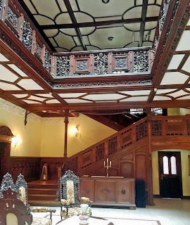 Grand wooden staircase in ornate historic hotel interior with decorated ceiling and yellow walls