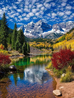 Maroon Bells mountains with snow reflected in a clear alpine lake surrounded by autumn foliage in Colorado