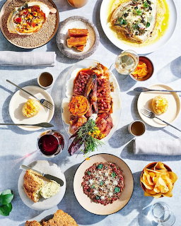 Overhead view of various breakfast dishes including eggs, beans, toast, and pancakes on plates with drinks