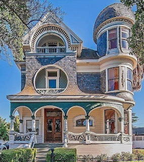Elaborate Victorian mansion with turret, ornate trim, and wraparound porch under blue sky