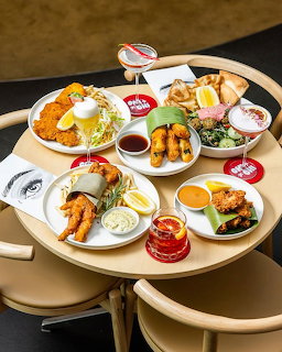 Overhead view of brunch table with multiple plates of eggs, fried foods, salads, and drinks on tiered serving trays