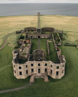 Aerial view of Downhill House ruins, a grand 18th-century mansion with symmetrical wings on coastal green grounds