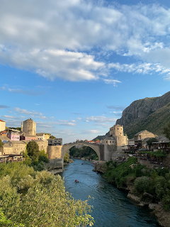 Stari Most old bridge in Mostar spanning the Neretva River with stone buildings and mountains behind