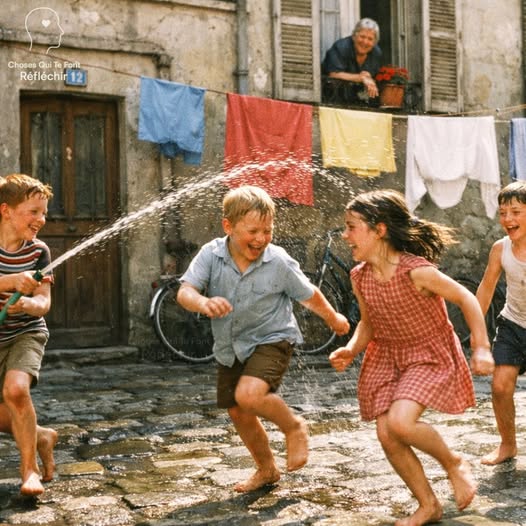 Group of children playing with water in a narrow street lined with old buildings and hanging laundry