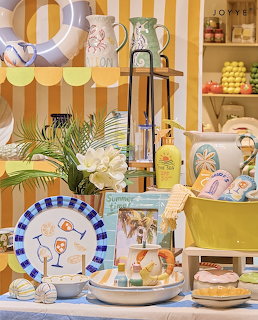 Cheerful kitchen display with yellow striped wall, ceramic pitchers, decorative plates, lemons and pastel accessories