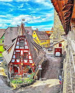 Half-timbered houses along a narrow street in a historic village with a bright blue sky