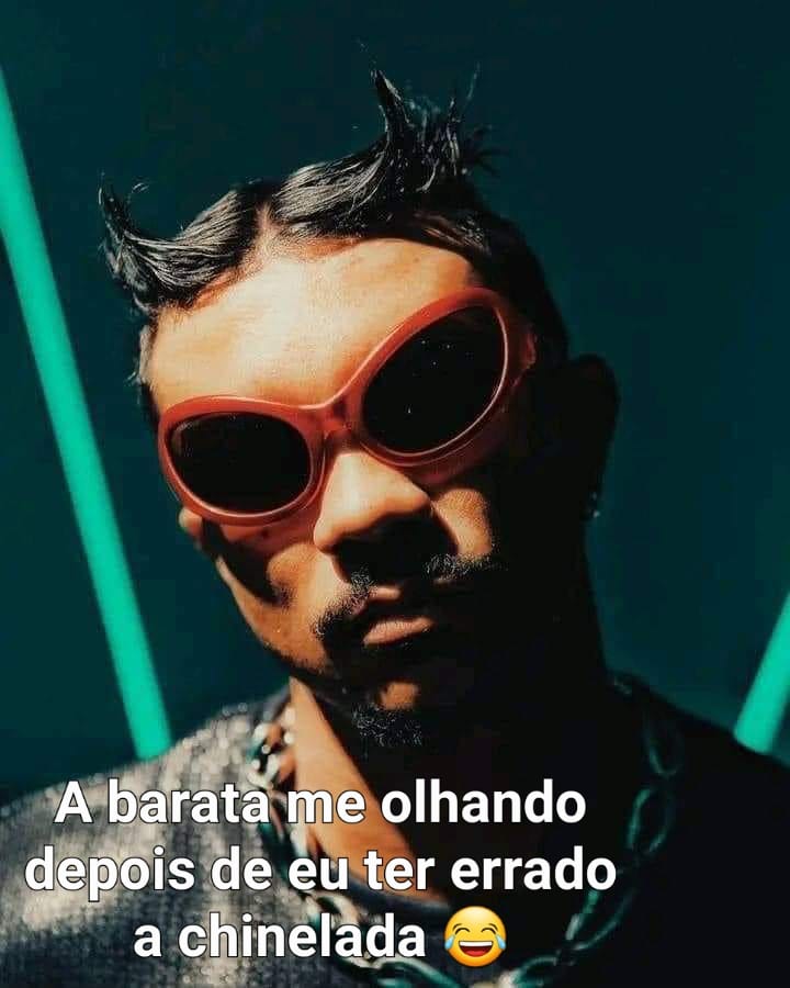 Young man with red oval sunglasses and a beard posing with dramatic teal lighting and a Portuguese meme caption