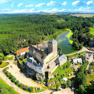 Aerial view of Kost Castle beside a lake and forest in the Czech countryside