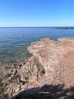 Rocky shoreline beside a calm blue sea under a clear sky