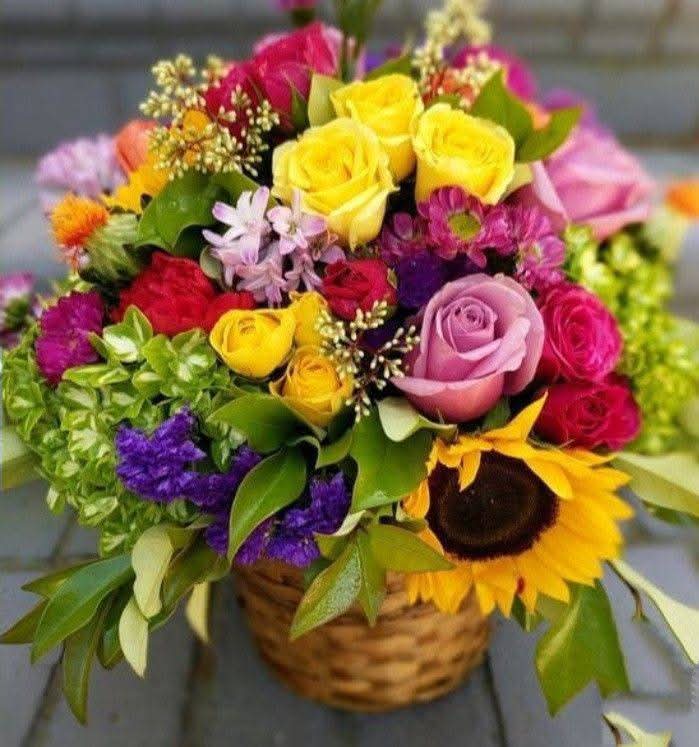 Colorful flower bouquet with roses, sunflowers, and mixed blooms in a woven basket