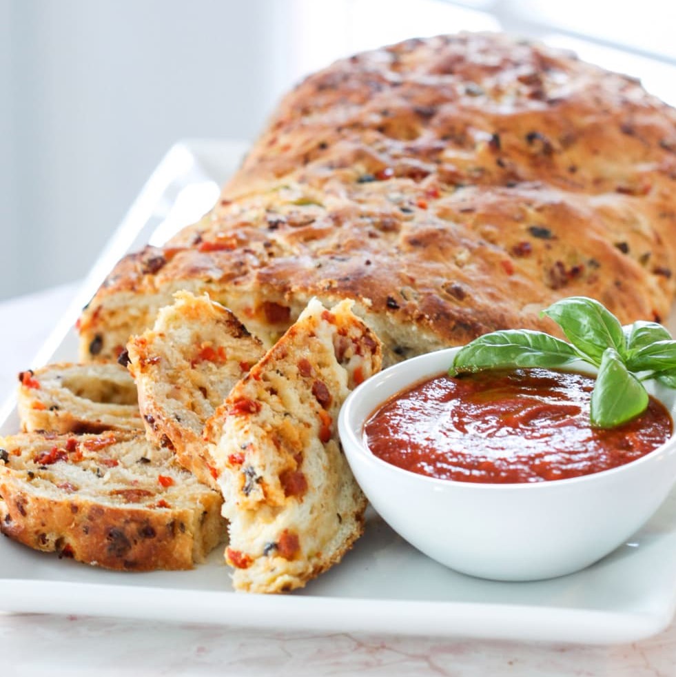 Sliced pizza bread with cheese and herbs on white plate with marinara sauce