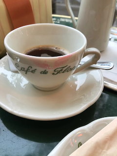 White Café de Flore coffee cup with black coffee and lipstick stain on rim, on saucer in cafe