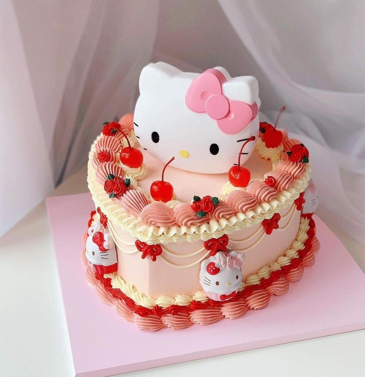 Two-tier white frosted cake with strawberries and Hello Kitty topper