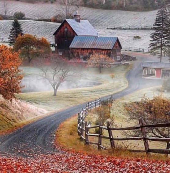 Misty autumn scene of Sleepy Hollow Farm with red barns, winding road, and fall foliage in Vermont