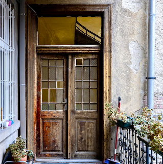 Aged wooden double door with glass grid panels in old apartment building entrance