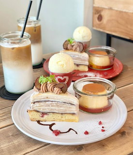 Layered cake, flan custard, and iced coffee drinks arranged on white plates with macarons
