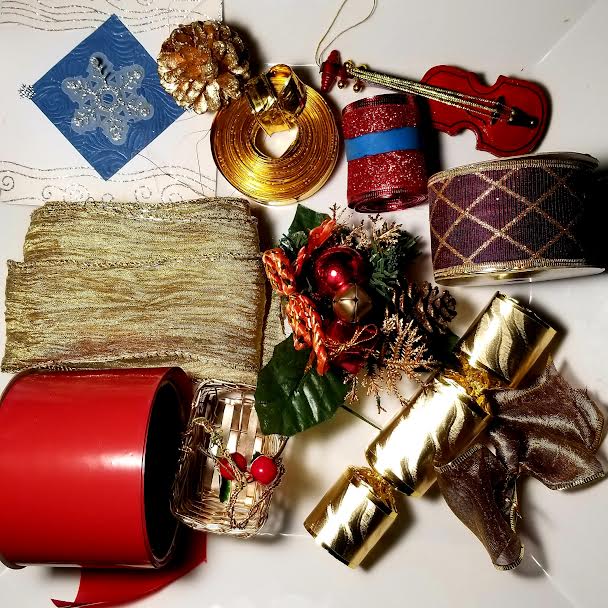 Christmas craft supplies with ribbons, bells, violin ornament, and festive decorations on a white background