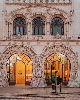 Ornate stone facade of Rossio Station in Lisbon with horseshoe arch entrances and decorative windows at dusk