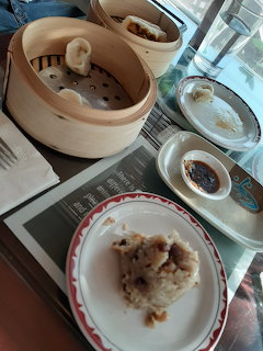 Dim sum meal with bamboo steamers, dumplings, rice and dishes on table