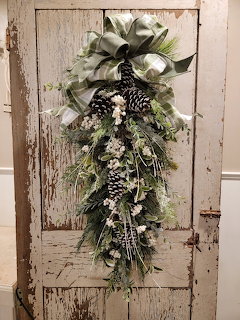 Winter swag wreath with white ribbon and pinecones on a distressed wooden door