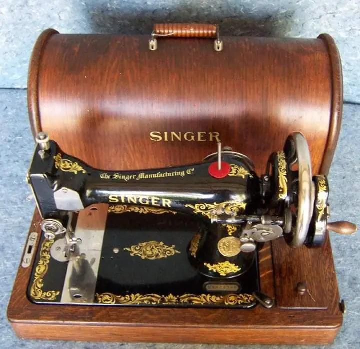 Vintage black Singer sewing machine with gold decorative flourishes and wooden case