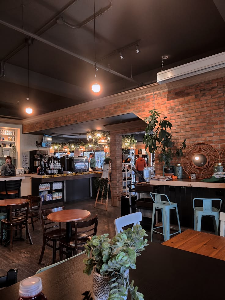 Cozy coffee shop interior with exposed brick wall, wooden tables, bar stools, and green plants