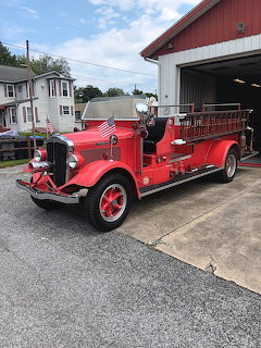 Antique red fire truck with brass details parked in front of fire station