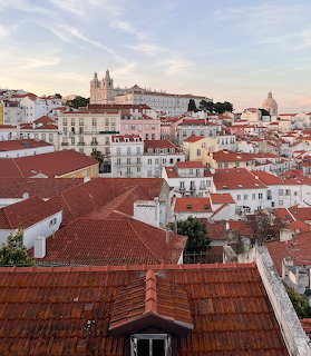 Red-tiled rooftops of Lisbon with historic buildings and a hilltop church
