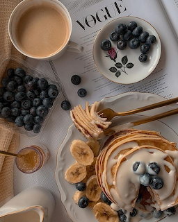 Overhead view of pancakes with blueberries, coffee, and fresh berries on a table