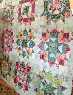 Colorful patchwork quilt with geometric star blocks in pink, green, and blue fabrics
