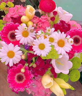 Colorful bouquet with pink daisies, gerberas, ranunculus, yellow tulips, and green mums