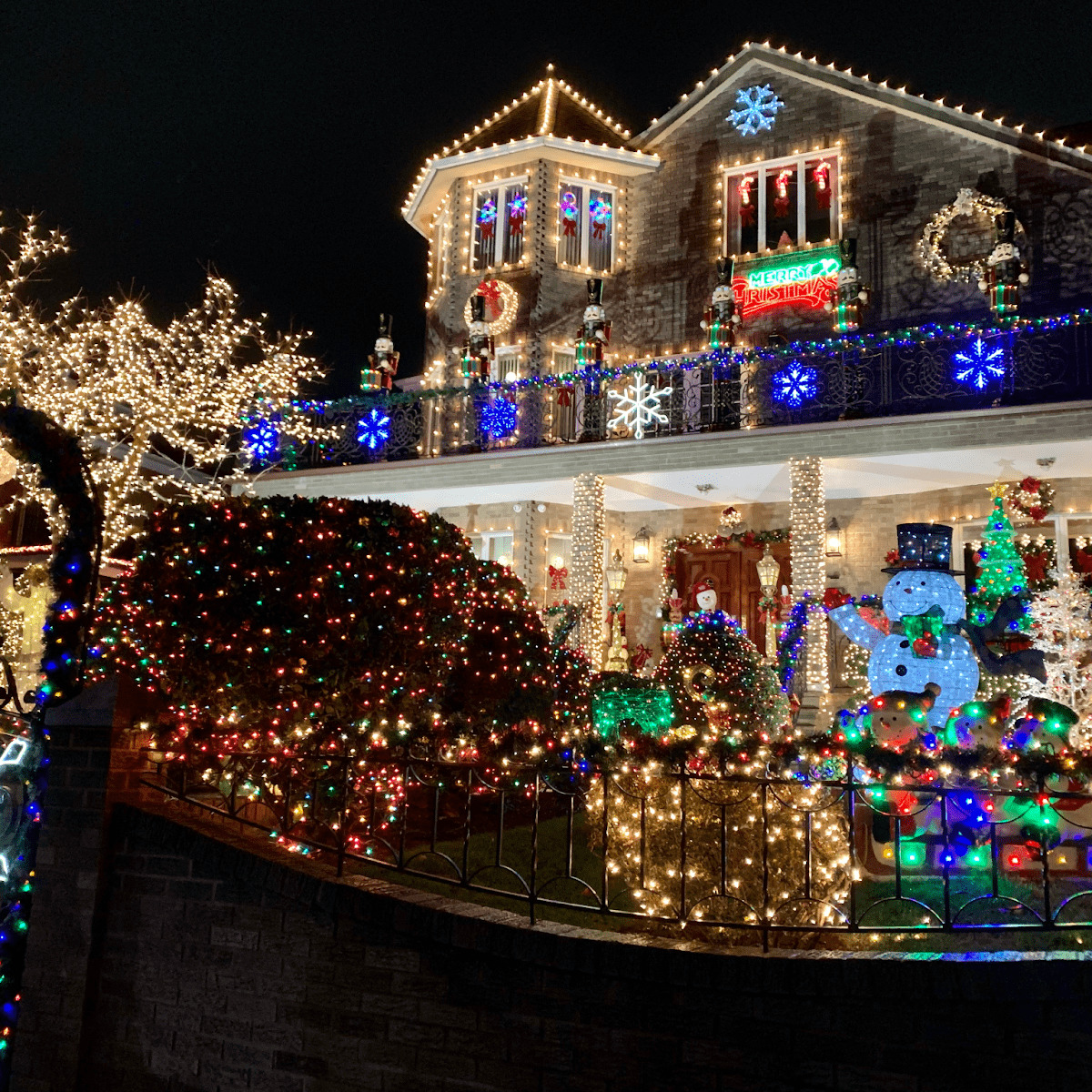 House decorated with multicolored Christmas lights, wreaths, and illuminated yard decorations at night