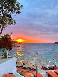 Sunset over sea with beach umbrellas on terrace in Ksamil, Albania