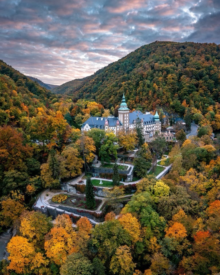 Castle-like estate surrounded by autumn forest in a mountain valley