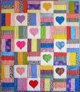 Colorful patchwork quilt with striped rail fence blocks and heart appliques in multiple fabrics