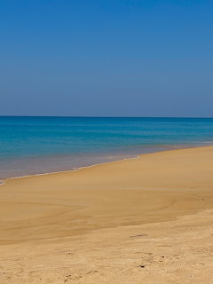 Sandy beach with calm turquoise sea and clear blue sky