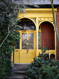 Ornamental yellow Victorian front door with stained glass,retwork arches, and red brick facade