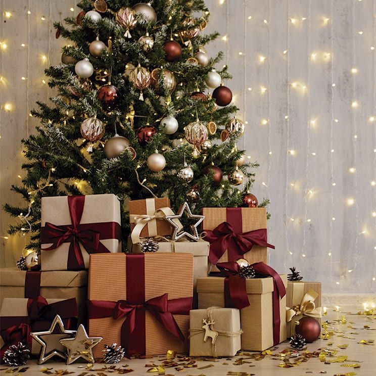 Christmas tree with ornaments and wrapped presents beneath, with bokeh lights in background