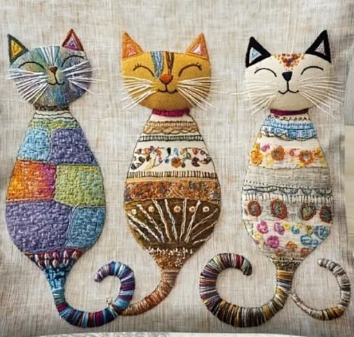 Three decorative folk art cats with patterned bodies and curled striped tails arranged in a row
