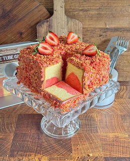 Strawberry-topped layer cake on a glass cake stand with a slice removed