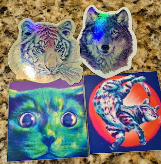 Four colorful animal stickers: white tiger, wolf, neon cat, and koi fish on granite countertop