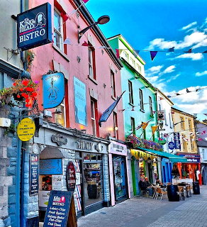 Colorful buildings and shops lining a street in Galway, Ireland on a sunny day