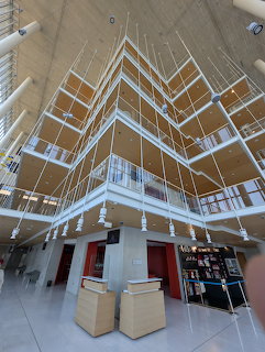 Dramatic angular wooden ceiling with white geometric beams and glass walls in modern cultural center interior