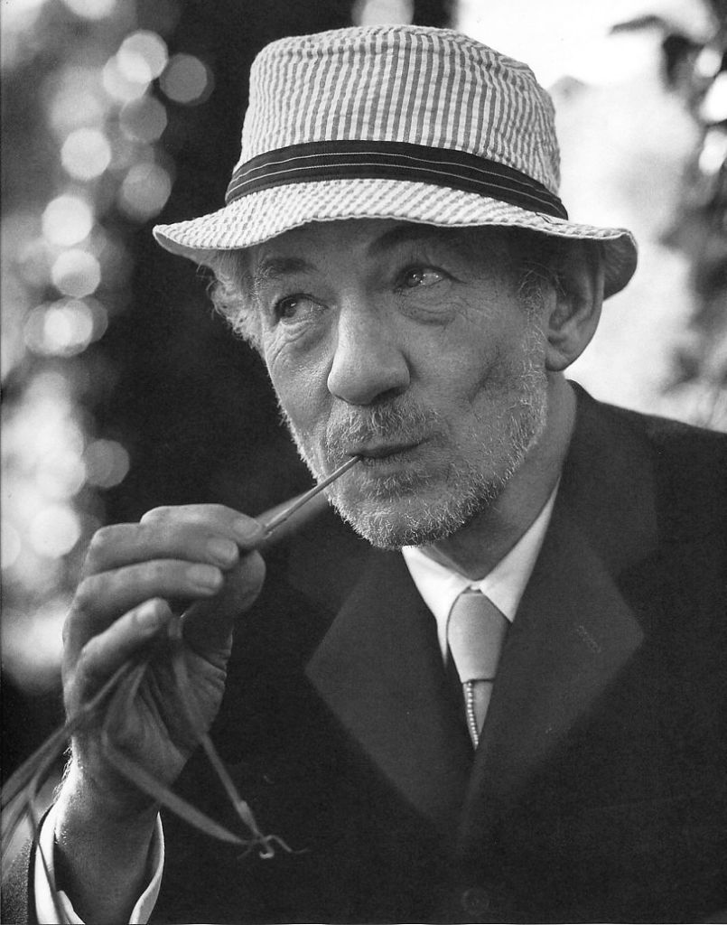 Black-and-white portrait of an older man in a hat and suit holding a pipe